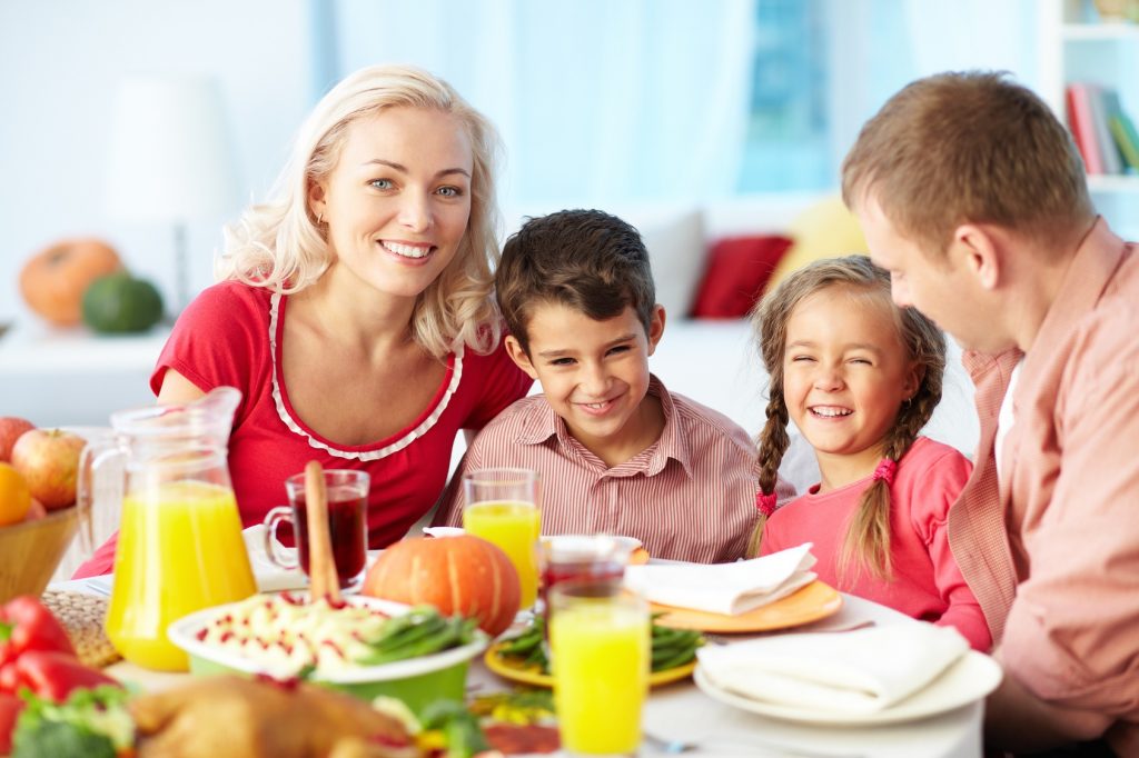 Portrait of happy family gathered at festive table on Thanksgiving Day